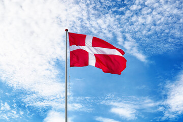 Danish flag on blue sky. Flag of Denmark waving in the wind. Bright and colourful concept for travel and tourism.