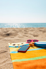 Towel, sunsreen, sunglasses and smart phone on the beach. Summer concept.