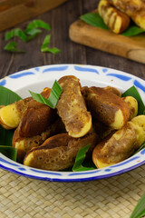 Kue Pukis, Indonesian popular traditional sweet cake, made from flour, eggs, sugar, milk or coconut milk, served on enamel plate,  usually at tea time or snack time.  Dark wooden background.