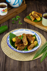Kue Pukis, Indonesian popular traditional sweet cake, made from flour, eggs, sugar, milk or coconut milk, served on enamel plate,  usually at tea time or snack time.  Dark wooden background.