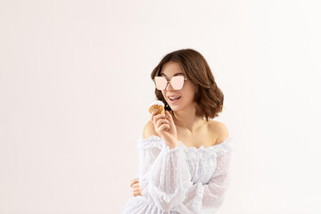 beautiful young woman in white dress with vanilla ice cream in a waffle cone. soft light. space for text