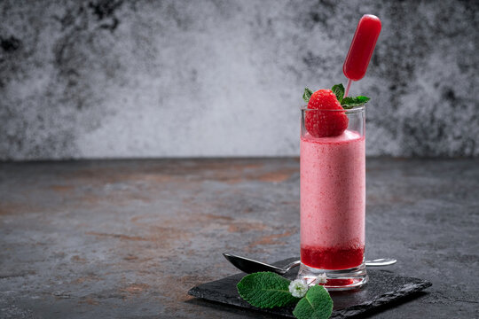 Raspberry Mousse With Syrup And Fresh Raspberries On Top In Glass Jars On A Stone Background. Berry Dessert With Whipped Cream, Copy Space