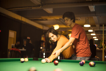Below view of happy couple playing billiard in a pool hall.