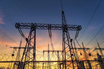 silhouette of high voltage power lines against a colorful sky at sunrise.