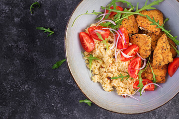Boiled bulgur, roasted chicken nuggets and fresh tomatoes salad. Middle eastern cuisine. Top view, flat lay
