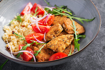 Boiled bulgur, roasted chicken nuggets and fresh tomatoes salad. Middle eastern cuisine.