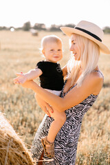 happy family walks in the field near the haystack at sunset, mom dad and two sons, the family is happy with smiles on their faces, hug the children