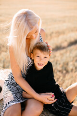 happy family walks in the field near the haystack at sunset, mom dad and two sons, the family is happy with smiles on their faces, hug the children