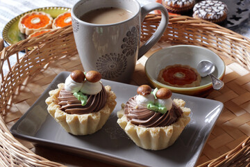 Close-up of tartlet cakes with chocolate cream and cup of coffee