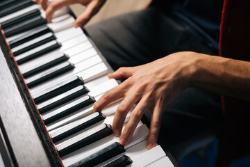 Top view of unrecognizable musician man playing on synthesize at home studio. Close-up hands of pianist male playing on digital piano in living room. Concept of music education.