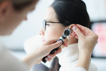 Otorhinolaryngologist examines patient ear with an otoscope