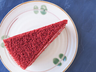 Top view piece of red velvet cake in soft brown plate on black stone background. Copy space for your text...