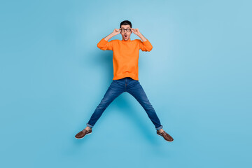 Full size portrait of shocked young man jumping open mouth staring arms touch eyewear isolated on...