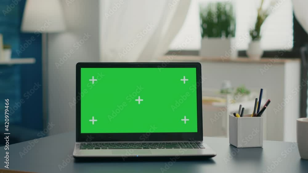 Poster laptop computer with mock up green screen chroma key standing on home office desk with nobody in it.