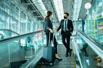 Business New normal concept.Businessman and woman wear face mask on escalator at terminal airport,...