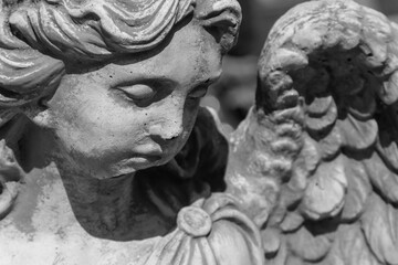 Fragment of an ancient statue isolated on black background. Sad angel as symbol of death and end of...