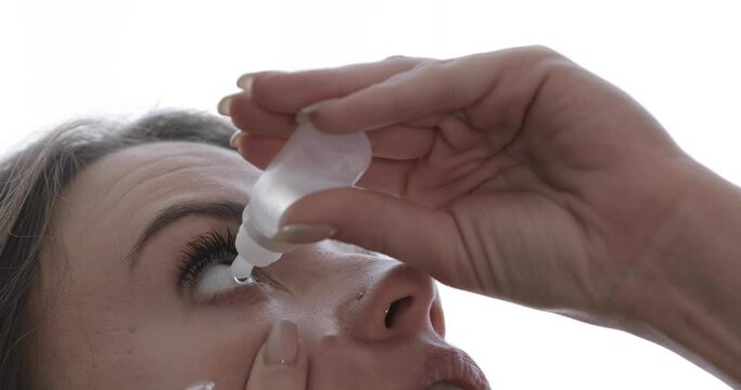 A young girl instills drops of dryness into her eyes. Close-up