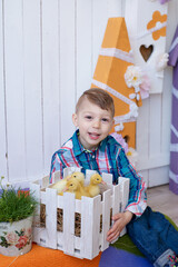 a boy in a good mood plays with an Easter bunny and little yellow ducklings, joy on the baby's face