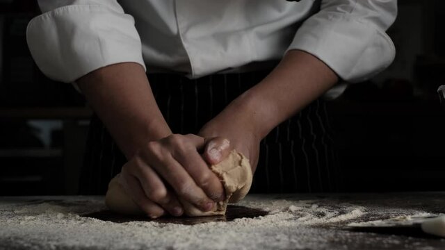 Bakery chef kneeding dough on wooden table. Baking concept.