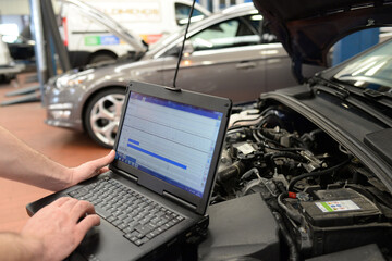 mechanic in a workshop checks and checks the electronics of the car - software update with a modern...