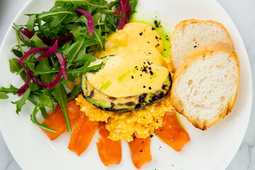 a mix of salmon, arugula salad, white bread and baked avocado with cheese. Light background