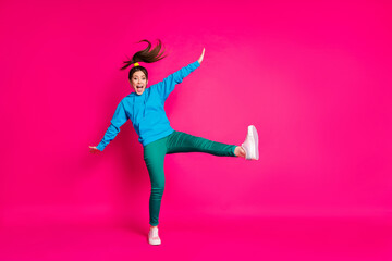 Full length photo of funny excited young lady wear blue sweater dancing standing one leg isolated bright pink color background