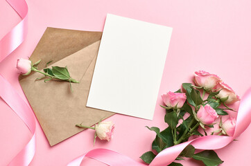 Greeting card mockup with envelope, pink ribbon and fresh roses on paper background