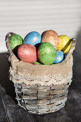 Easter colored eggs in a basket on dark wooden background.