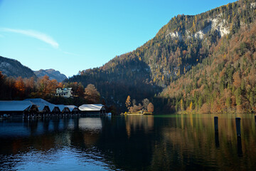 Am Ufer des K&ouml;nigssees im Sp&auml;therbst mit Blick auf die Bootsh&auml;user und der Insel Christlieger die von der Sonne angestrahlt wird