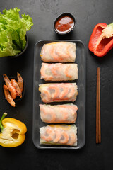 Asian food spring rolls with vegetables, shrimps in rice paper on black background. View from above. Vertical orientation.