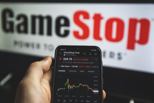 Holding mobile phone with stock market charts of