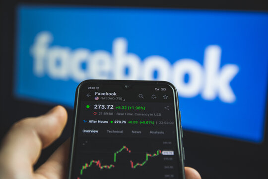 Holding mobile phone with stock market charts of Facebook company shares