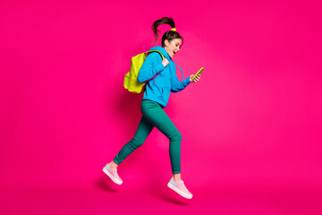 Fototapeta na wymiar Full length photo of impressed funny young woman dressed blue hoodie rucksack typing modern device isolated pink color background