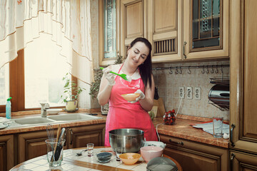 A young brunette woman prepares pastries in her kitchen.