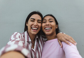Happy Latin women taking selfie with smartphone camera
