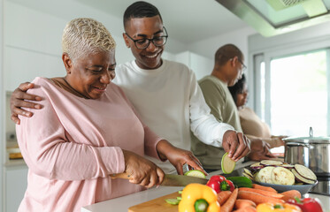 Happy African family having fun in modern kitchen preparing food recipe with fresh vegetables - Food and parents unity concept