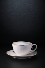 Morning coffee in Italy. White cup of cappuccino on a black textured background. Italian cappuccino. Coffee on black. Close-up on a white cup.