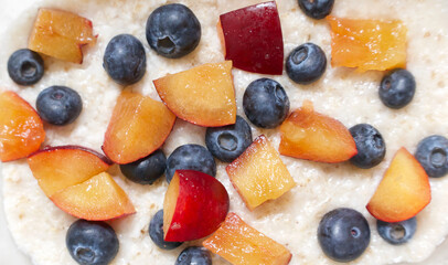 Full frame healthy breakfast background with porridge blueberries and plums