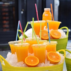 a bunch of orange juice glasses inside a bucket of ice 