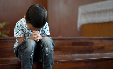 Young Christian Asian Boy Sitting on Steps Praying to God at Church with Hope and Faith