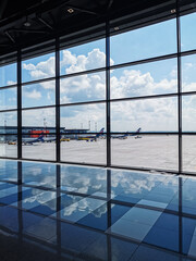 View looking out to airport with aircraft, blue sky and clouds