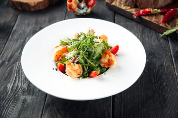 Shrimp and arugula greens gourmet salad on the wooden table