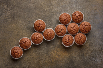 Chocolate homemade cupcakes are lined with flower shapes, copy space, top view