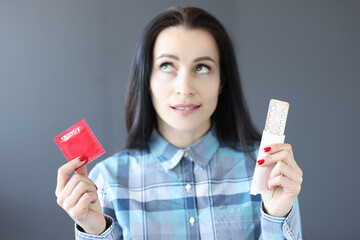 Young woman chooses between birth control pills and condom
