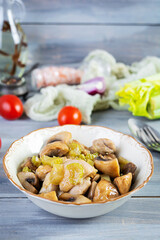 Stew chicken thighs with mushrooms, celery, onion and pepper. Stir fry chicken on wooden background