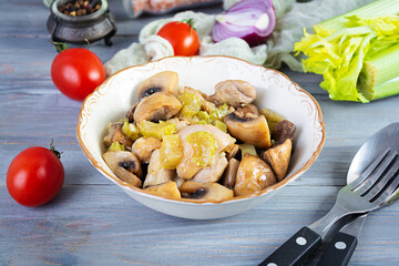 Stew chicken thighs with mushrooms, celery, onion and pepper. Stir fry chicken on wooden background