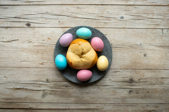 small easter bread pinze with small colorful easter eggs on wooden background photo taken from above