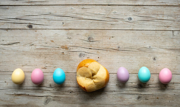 small easter bread pinze with small colorful easter eggs on wooden background photo taken from above