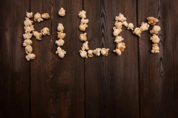 Obraz na płótnie Canvas popcorn laid out word movie on wooden background snack
