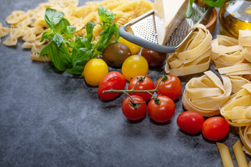 Mixed dried pasta selection on wooden background. composition of healthy food ingredients isolated on black stone background, top view, Flat lay.